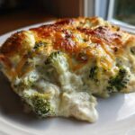 A close-up of a creamy, cheesy slice of Chicken Divan casserole with visible broccoli florets.