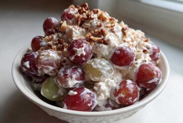 A white bowl filled with creamy chicken salad chick grape salad, topped with chopped pecans.