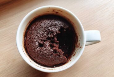 Overhead view of a freshly baked chocolate mug cake in a white mug, with a piece already scooped out.