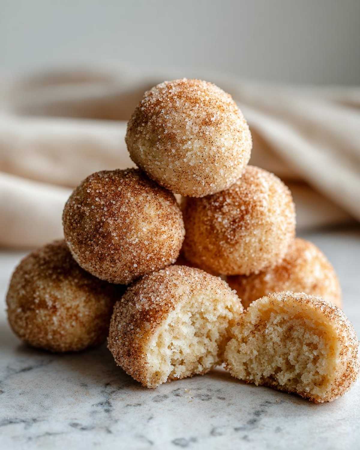 A stack of soft cinnamon sugar snowball cookies, one broken open to show the texture.