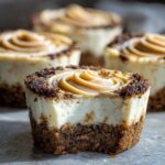 Close-up of a cookie butter cheesecake cup with a bite taken out, showing the creamy filling and crust.