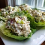 Close-up of cottage cheese chicken salad served in crisp lettuce cups, garnished with dill.