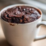 A rich, dark chocolate Cottage Cheese Microwave Brownie baked perfectly inside a white ceramic mug.