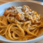 A close-up of creamy Cajun chicken pasta tossed in a rich sauce, topped with grated cheese and herbs.