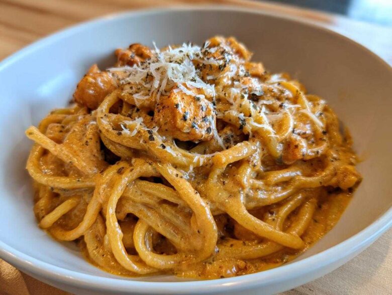 A close-up of creamy Cajun chicken pasta tossed in a rich sauce, topped with grated cheese and herbs.