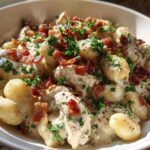 Close-up of creamy crack chicken gnocchi tossed in a rich white sauce, topped with bacon bits and fresh parsley.
