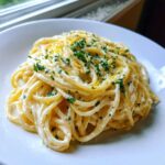 A close-up serving of rich, Creamy Lemon Pasta tossed in a white sauce, topped with fresh parsley and lemon zest.