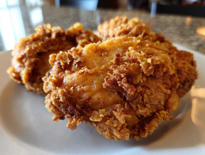 Close-up of several pieces of golden brown, crispy fried chicken resting on a white plate.