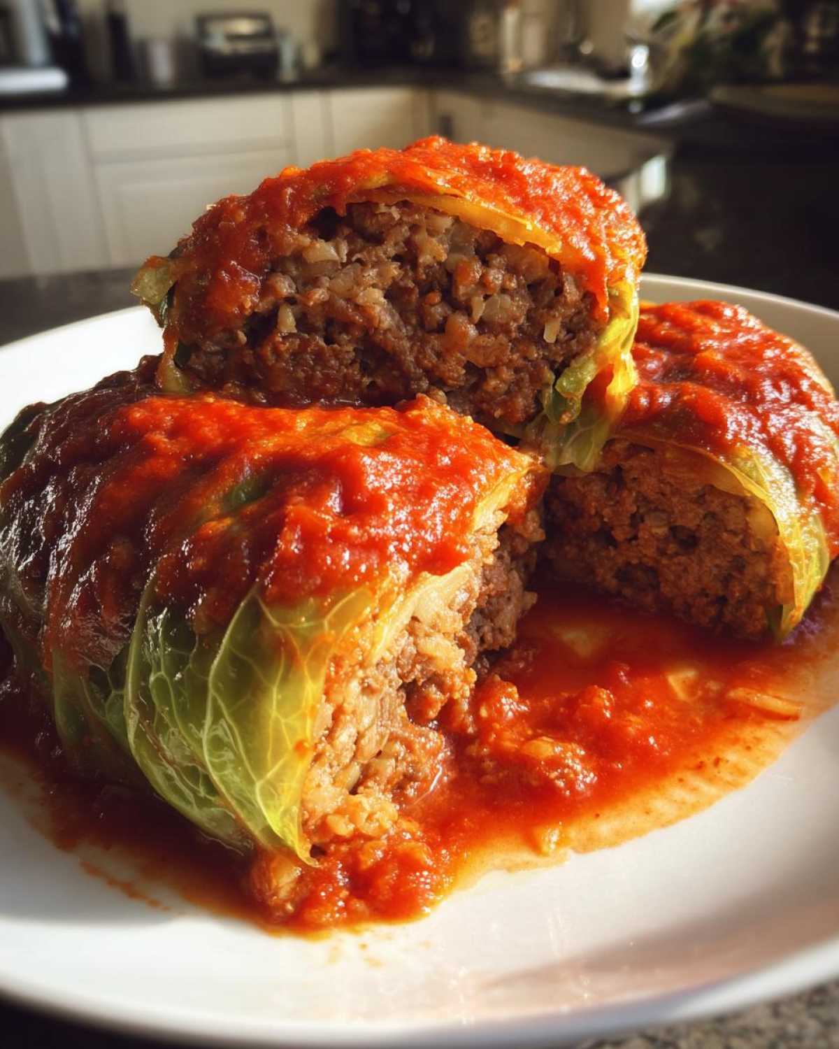 Close-up of two halved cabbage rolls showing the savory meat and rice filling, topped generously with bright red tomato sauce.