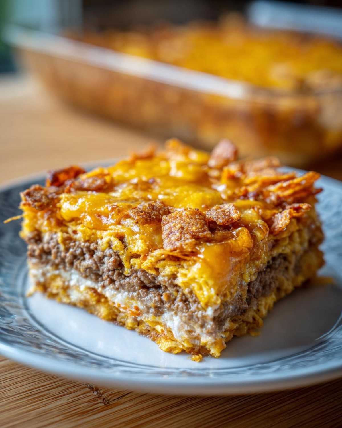 A thick slice of Dorito Casserole featuring layers of seasoned beef, creamy sauce, and a cheesy, crunchy Dorito topping.