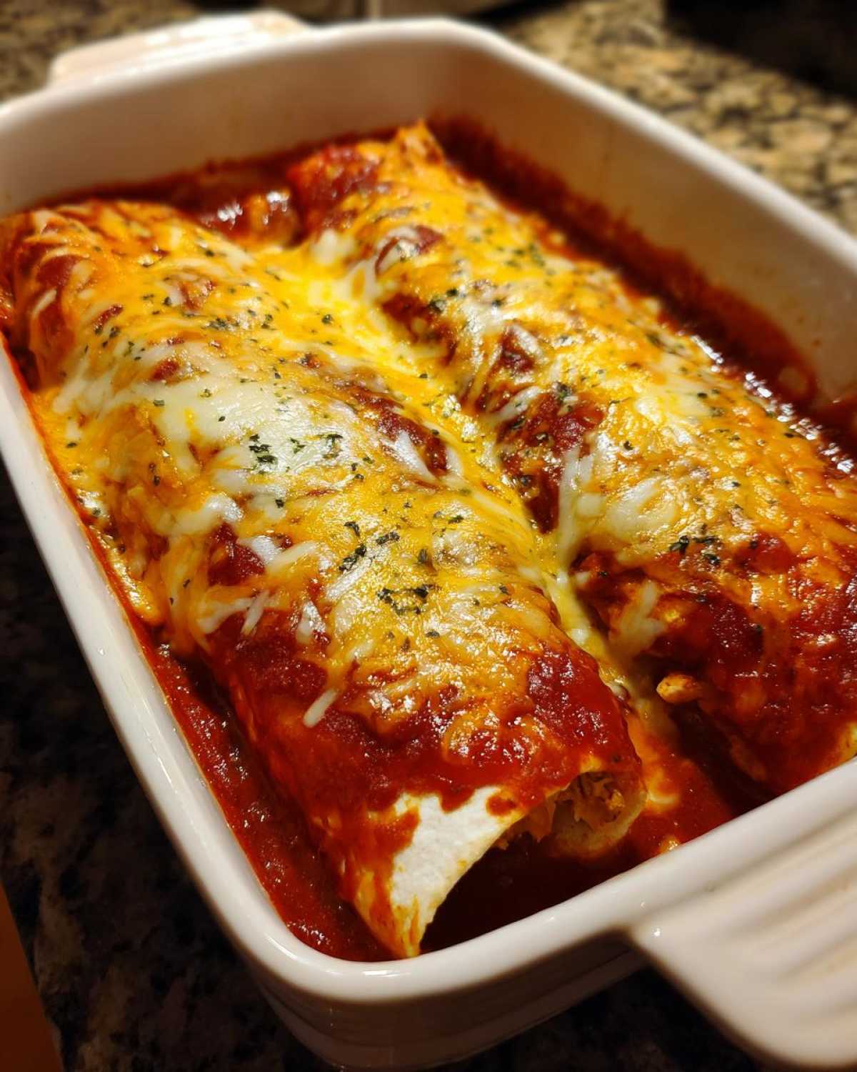 Close-up of baked easy chicken enchiladas covered in melted cheddar and Monterey Jack cheese and red sauce.