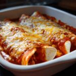 Close-up of baked easy chicken enchiladas smothered in red sauce and melted cheddar and Monterey Jack cheese.