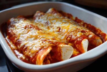 Close-up of baked easy chicken enchiladas smothered in red sauce and melted cheddar and Monterey Jack cheese.