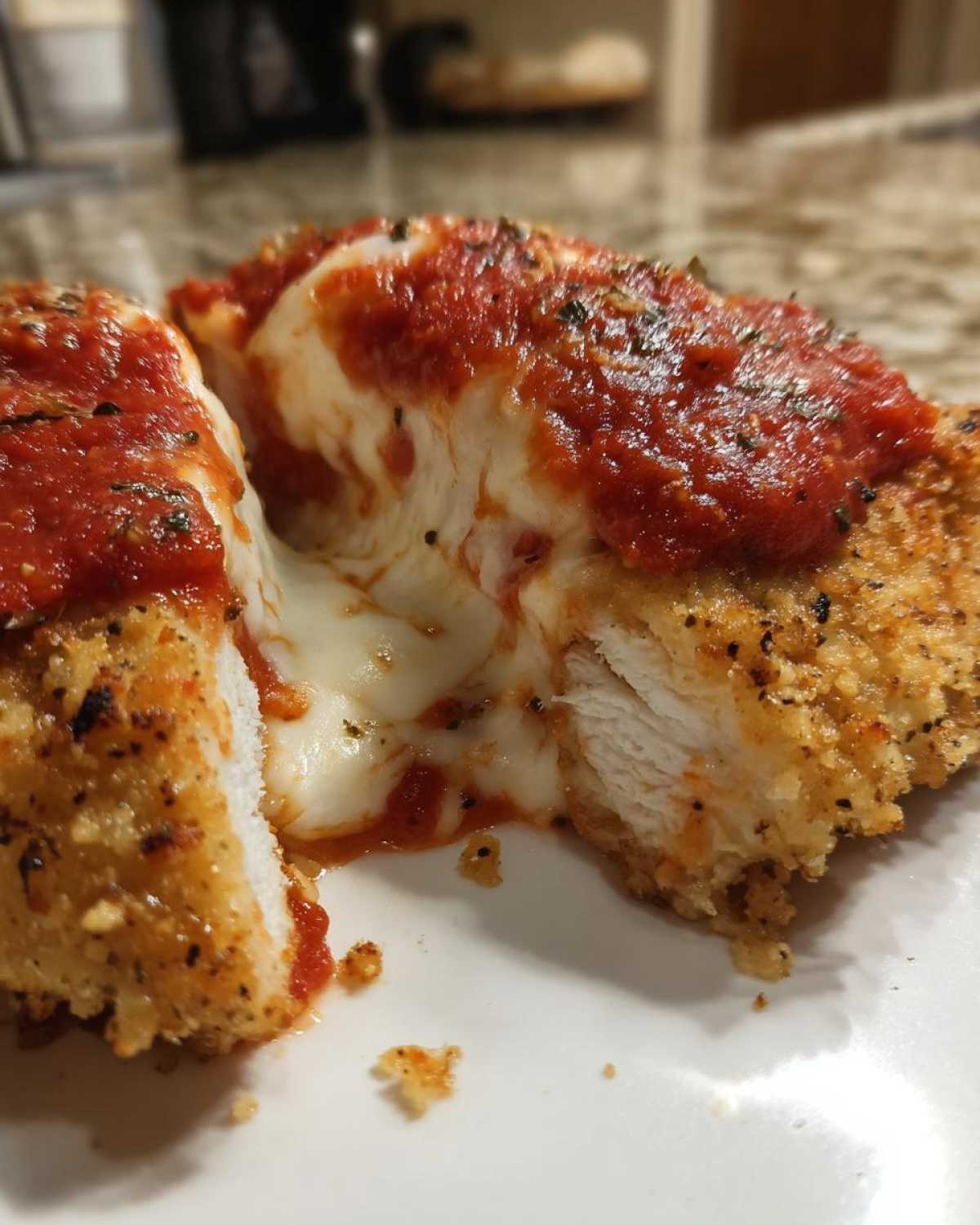 Close-up of Easy Chicken Parmesan cut in half showing melted mozzarella cheese pull, marinara sauce, and crispy breading.