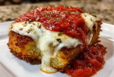 Close-up of a breaded chicken breast topped with melted mozzarella, marinara sauce, and herbs for Easy Chicken Parmesan.
