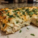 Close-up of a slice of cheesy Fiesta Lime Chicken bake showing melted cheese and herbs.