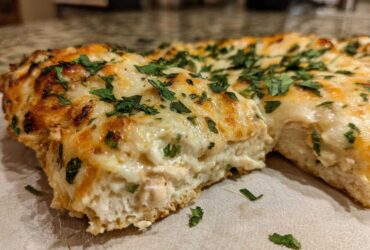 Close-up of a slice of cheesy Fiesta Lime Chicken bake showing melted cheese and herbs.