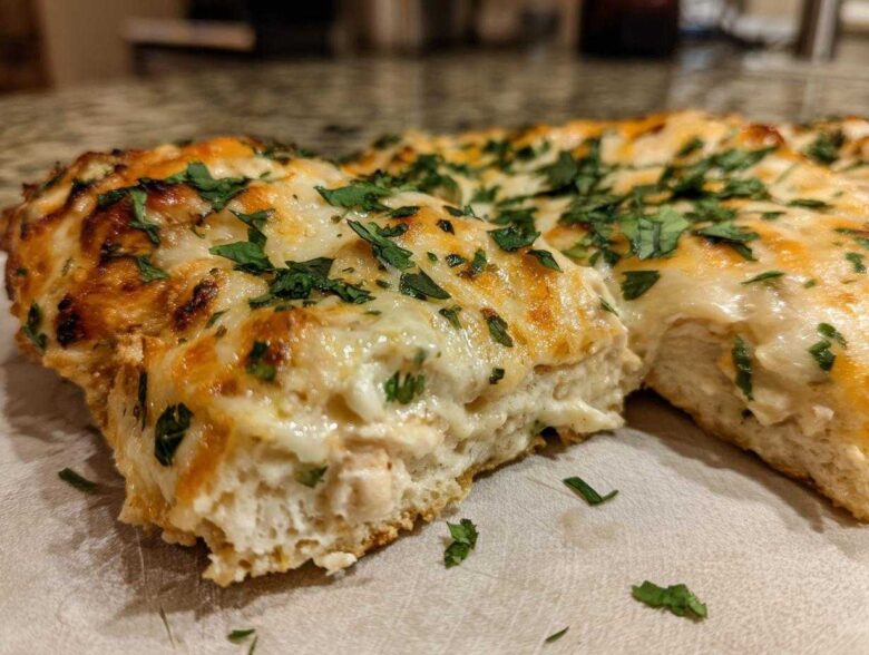 Close-up of a slice of cheesy Fiesta Lime Chicken bake showing melted cheese and herbs.