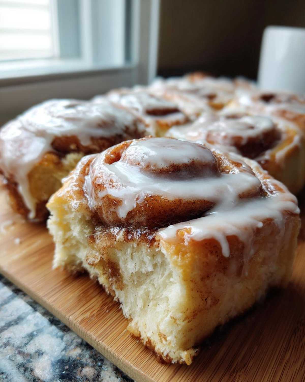 Close-up of a fluffy cinnamon roll with thick white icing, showing the soft interior texture.