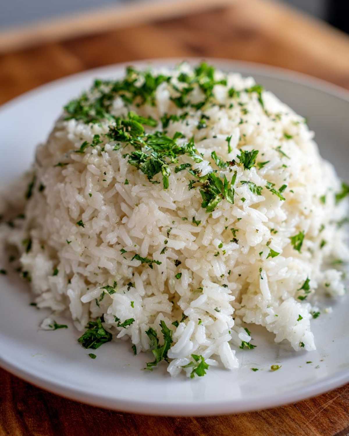 A mound of fluffy white rice seasoned with garlic butter and generously topped with chopped fresh parsley.