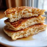 Close-up view showing the fluffy, airy interior texture of a stack of sourdough pancakes drizzled with syrup.