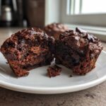 Close-up of fudgy chocolate zucchini muffins cut in half showing moist interior and chocolate chips.
