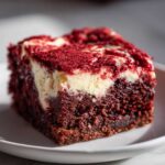 Close-up of a fudgy red velvet brownie square featuring a rich cream cheese swirl topping.