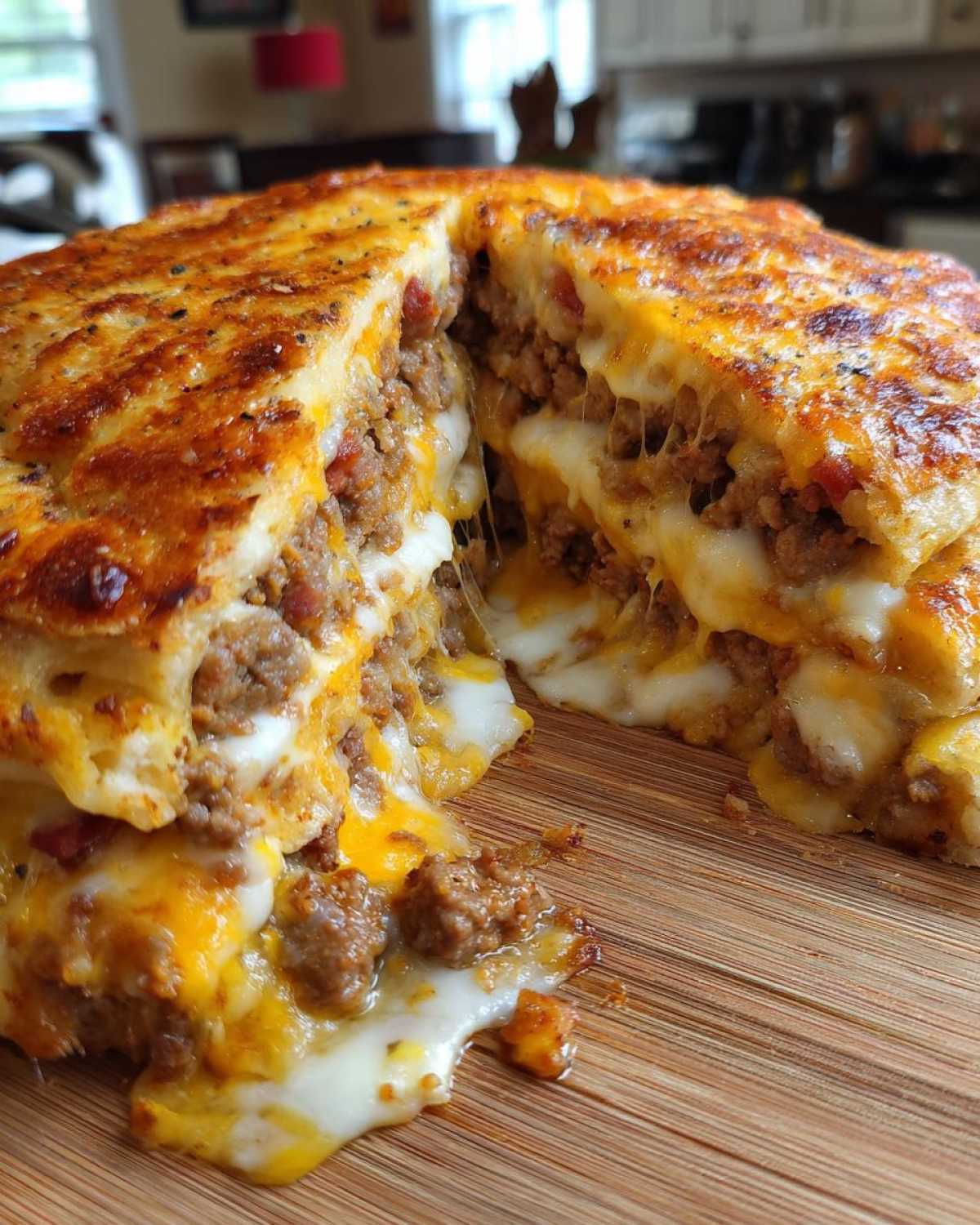 Cross-section of a baked garbage bread showing layers of seasoned meat and extremely melted, gooey cheese.