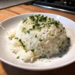 Close-up of fluffy white rice seasoned with garlic butter and topped generously with fresh chopped parsley.