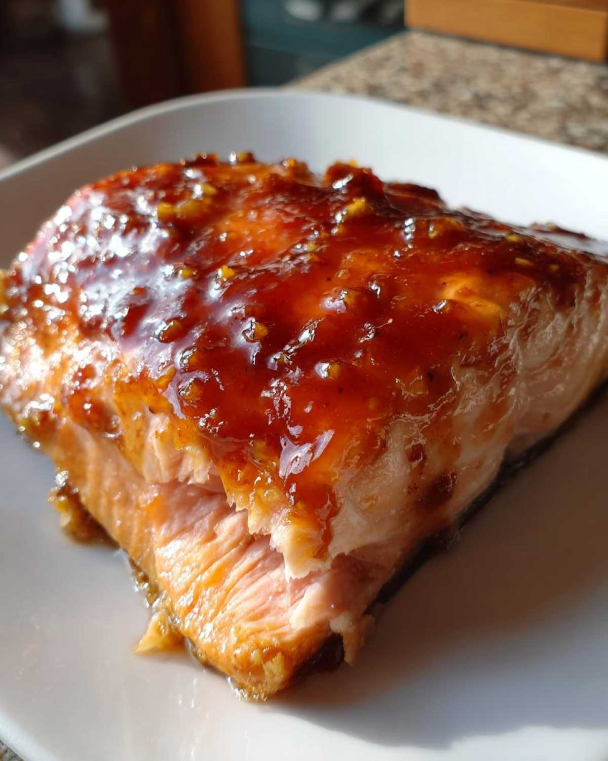 Close-up of a perfectly cooked salmon fillet topped with a thick, glossy, sweet and savory glaze.