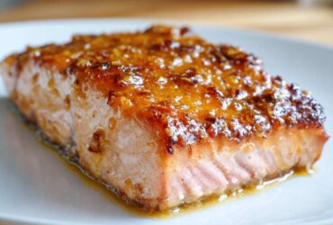 Close-up of a perfectly cooked salmon fillet with a thick, shiny, caramelized glaze on top.