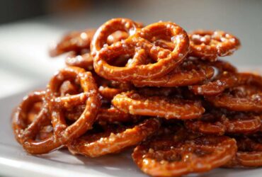 A close-up photo of a pile of shiny, glazed toffee pretzels catching the light.