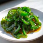 Close-up of bright green, glossy candied jalapenos sliced and glistening in syrup on a white dish.