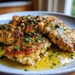 Close-up of pan-seared chicken piccata pieces covered in a bright lemon butter sauce, capers, and fresh parsley.