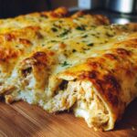 Close-up of three baked green chile chicken enchiladas covered in melted, browned cheese and parsley.