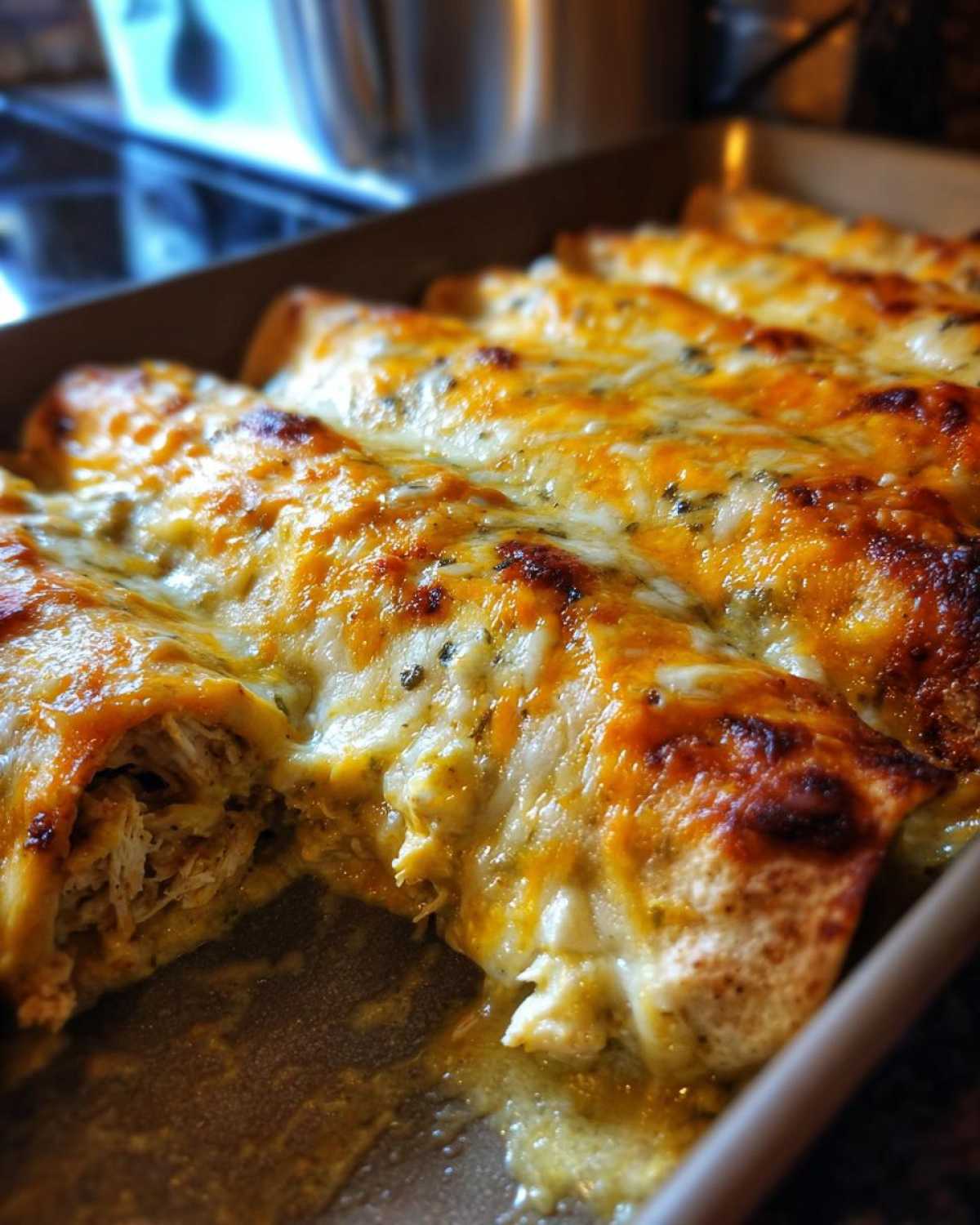 Close-up of baked green chile chicken enchiladas covered in melted, bubbly, browned cheese.