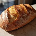 A beautifully baked loaf of Italian bread with a deeply scored, golden-brown, crusty exterior.