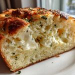 A close-up cross-section of soft Italian herb and cheese bread stuffed with melted cheese.