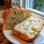 Close-up of a loaf of Italian herb and cheese bread, sliced to show the airy interior filled with herbs.