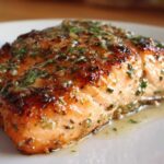 Close-up of a perfectly cooked, juicy air fryer salmon fillet topped with a glistening garlic herb glaze.