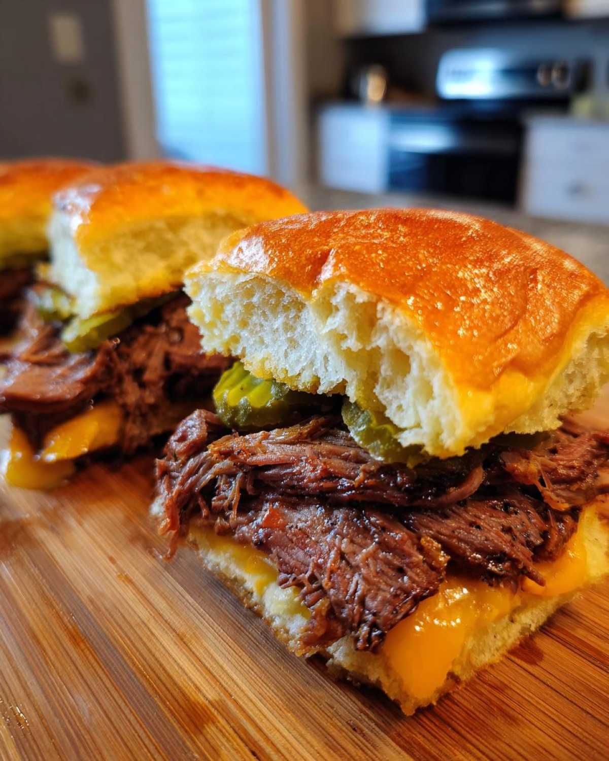 Close-up of Mississippi pot roast sliders featuring shredded beef, melted cheese, and pickles on soft buns.