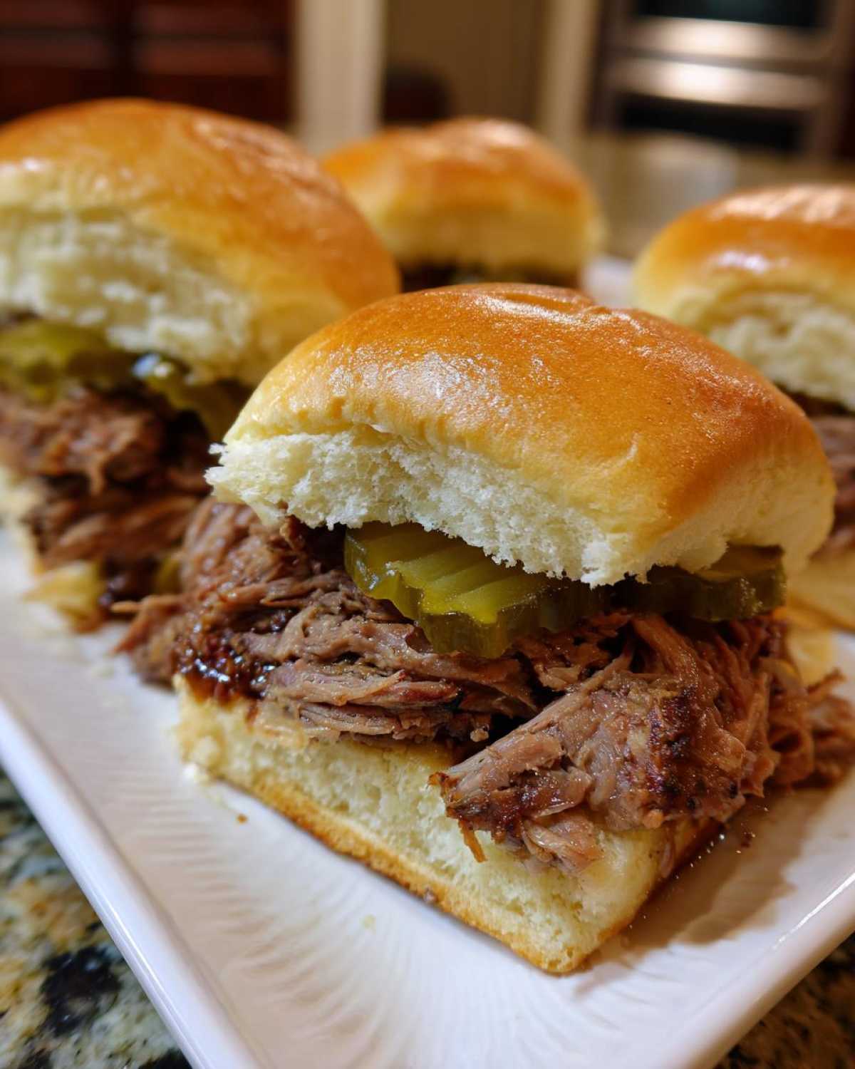 Close-up of delicious Mississippi pot roast sliders piled high with shredded beef and pickles on soft buns.