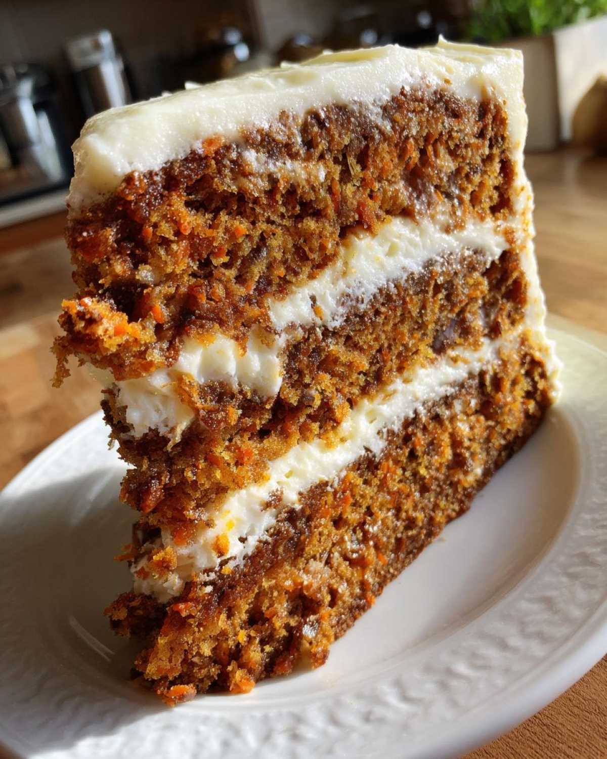 A tall, moist slice of carrot cake recipe with three layers of cake and two layers of thick cream cheese frosting.