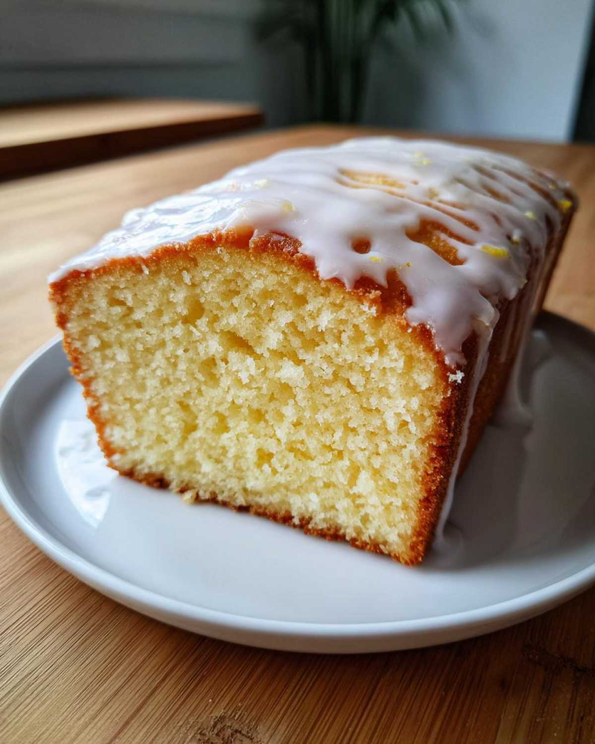 Close-up of a moist slice of lemon pound cake topped with a thick, white lemon glaze.