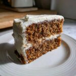 Close-up of a moist slice of spice cake layered with thick cream cheese frosting.
