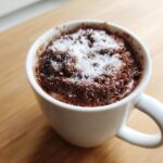 Close-up of a mug filled with rich, dark chocolate from hot cocoa mix, topped with coarse white sugar crystals.
