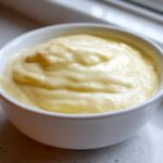 Close-up of creamy, rich Olive Garden Alfredo Sauce served in a small white bowl.