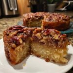 Close-up of a slice of pecan upside down cake showing the moist crumb and sticky pecan topping.