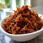 Close-up of a bowl filled with deeply browned, sweet caramelized onions ready for serving.