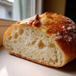 Close-up of the open crumb structure inside a freshly baked loaf of french bread with a golden crust.